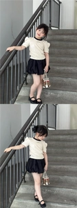 Detail of girls puff sleeve T-shirt and black skirt paired with a plaid mini bucket bag
