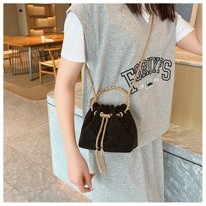 Close-up of black bucket bag with sparkling rhinestones, gold handles and chain strap