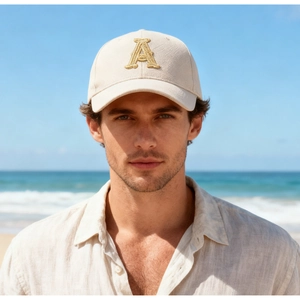 Close-up of golden letter A embroidery on a cream baseball cap with twill fabric texture