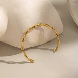 Detailed shot of gold twisted bangle with 18K plating on artistic sculpture display