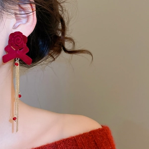 Close-up of vintage flower bow tassel earrings on model wearing a red sweater