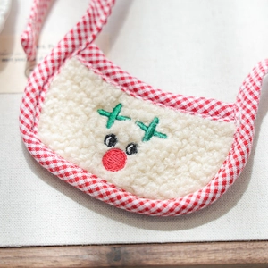 Macro shot of reindeer embroidery on a soft beige fleece pet bandana with red plaid trim