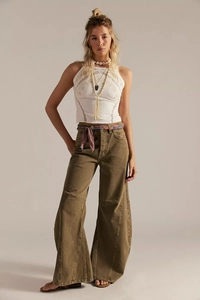 Détail d'un jean large taille haute olive et d'un haut licou en dentelle blanche brodée
