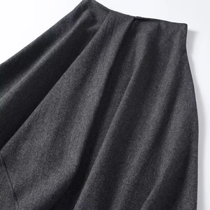 Gros plan du tissu de jupe plissée gris foncé montrant la texture épaisse et le drapé