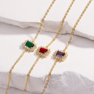 Bracelets dorés élégants avec zircons verts rouges et violets sur pierre blanche