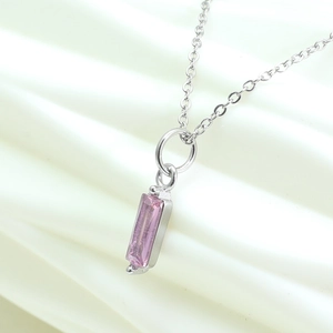 Detail shot of rectangular pink zircon pendant on silver chain over white fabric