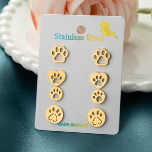 Golden stainless steel cat paw and heart stud earrings set on a decorative card