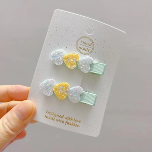 Close-up of glitter heart hair clips with light green ribbon wrap on a set of two