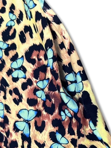 Close-up of knit fabric texture with yellow leopard print and blue butterfly patterns