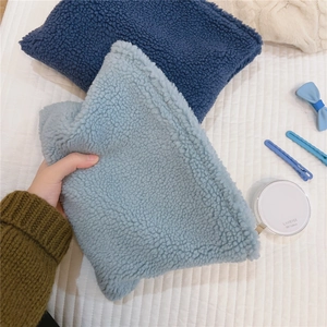 Detail of soft fleece winter makeup bags in deep and light blue colors on white fabric