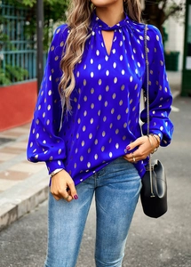 Detailed view of women's long sleeve blue blouse featuring gold polka dots and a V-neckline