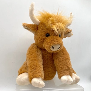 Close-up of brown Highland Cow plush toy with long fluffy fur and beige horns on white background