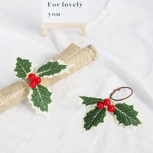 Luxuriöser Serviettenring zu Weihnachten mit roten Beeren und grünen Blättern auf weißem Stoff