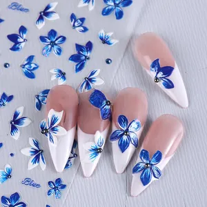 Detail of blue lily and bellflower embossed nail stickers on a white wooden background