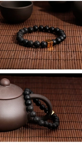 Detail of beaded bracelet with matte black and lava stone beads and gold rectangular accent