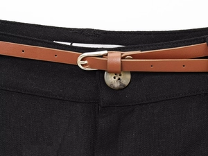 Detailed macro view of black linen shorts with tortoise shell button and brown slim belt