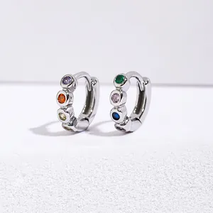 Minimalist silver hoop earrings with multicolored round gemstones on a white display