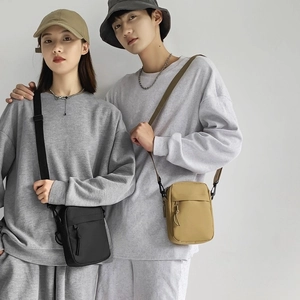 Unisex nylon crossbody bag in black and khaki shown on models for casual sports style