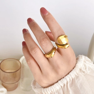 Detail of chunky gold curved rings featuring minimalist polished crossover design