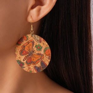 Close-up of bohemian cork round drop earrings with butterfly and floral print details