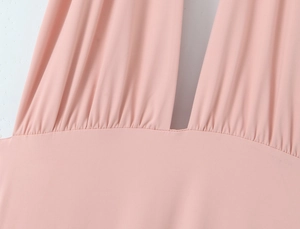 Détail d'une robe rose à décolleté en V profond avec taille plissée et tissu doux