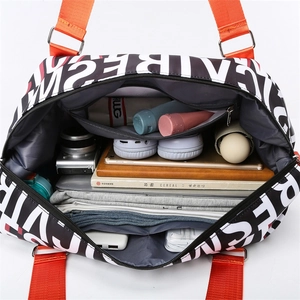 Black travel bag with orange straps and letter print, showing large capacity interior