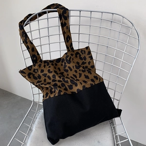 Detail of leopard print canvas tote bag with black stitching on a white chair