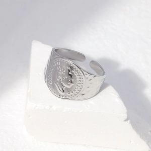 Detailed macro of silver queen portrait coin ring with handmade hammered texture finish