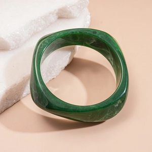 Close-up of a green resin marble-textured irregular square bangle on a neutral stone