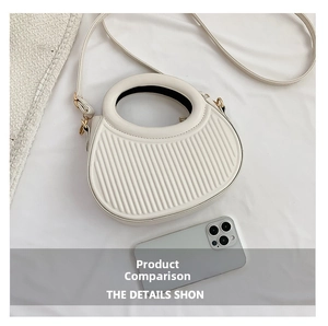 Detailed view of white crescent bag with vertical embossing and metal hardware details
