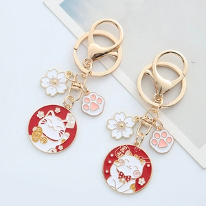 Japanese lucky cat keychains with cherry blossoms and pink cat paw charms in gold metal