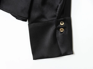 Dettaglio del polsino in raso nero con due eleganti bottoni dorati di forma tonda