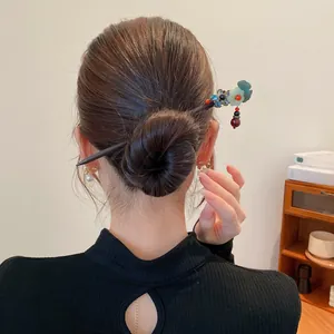 Détail d'un pic à cheveux en bois vintage avec fleur bleue et élégants glands perlés