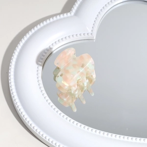 Detail of acetate hair claw clip with pink and green marble texture on a heart mirror