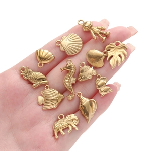 Detailed collection of gold ocean charms including seashells and seahorse on hand