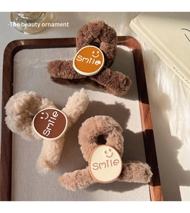 Detailed view of three plush smiley face hair claws in brown, beige, and khaki tones