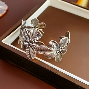 Detail view of a vintage oxidized metal flower cuff bracelet in a jewelry box