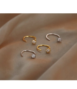 Detailed close-up of C-shaped earrings with round clear zircons on brown silk