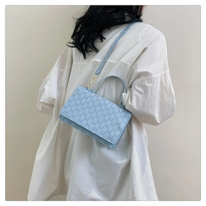 Detail of light blue crossbody bag with M letter embossing and gold-tone hardware detail