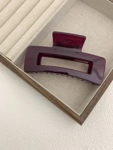 Macro shot of large wine red glossy acrylic rectangular hair claw clip in a wooden box