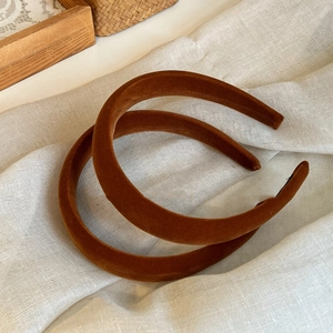 Detail view of two caramel velvet headbands with plush texture on linen fabric