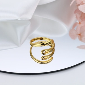 Dettaglio macro di anello a spirale dorato con incisione Faith e croce su seta
