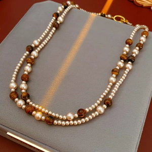 Détail du collier double rang avec perles blanches et pierres d'oeil de tigre brunes
