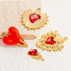 Detail of red and gold heart pendants on marble, featuring floral and flame designs