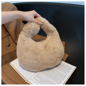 Close-up of beige faux fur handbag with round handle placed on an open book