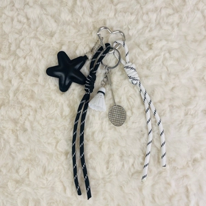 Detail of badminton keychain with shuttlecock, metal racket and woven cord charms