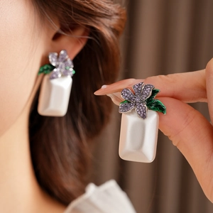 Gros plan sur des boucles d'oreilles perles carrées avec fleurs en cristal violet