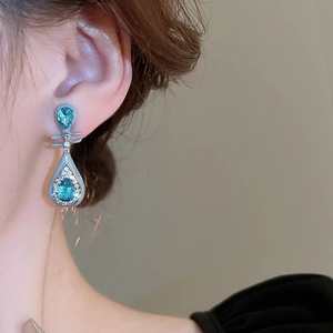 Detail shot of light blue pear-shaped gemstone earrings worn on model for a vintage look