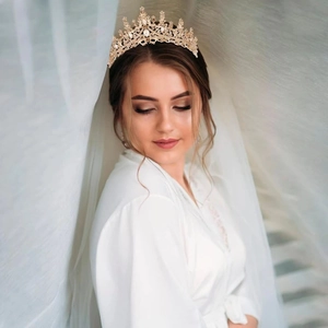 Detailed close-up of a gold bridal crown with intricate hollow patterns and white rhinestones