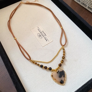 Detail of retro leather cord necklace with tiger eye resin heart pendant on display